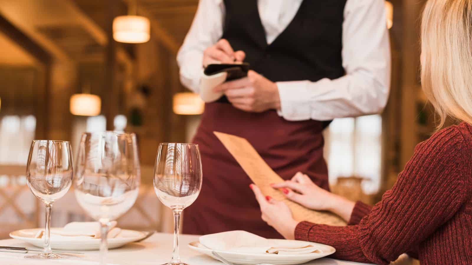 Woman ordering with a waiter on standby