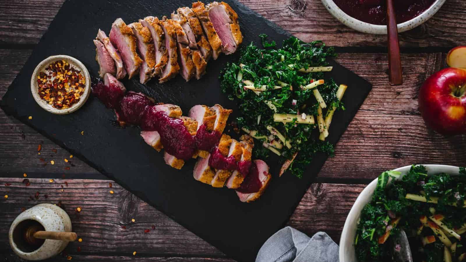 Overhead view of sliced duck breast with berry sauce.