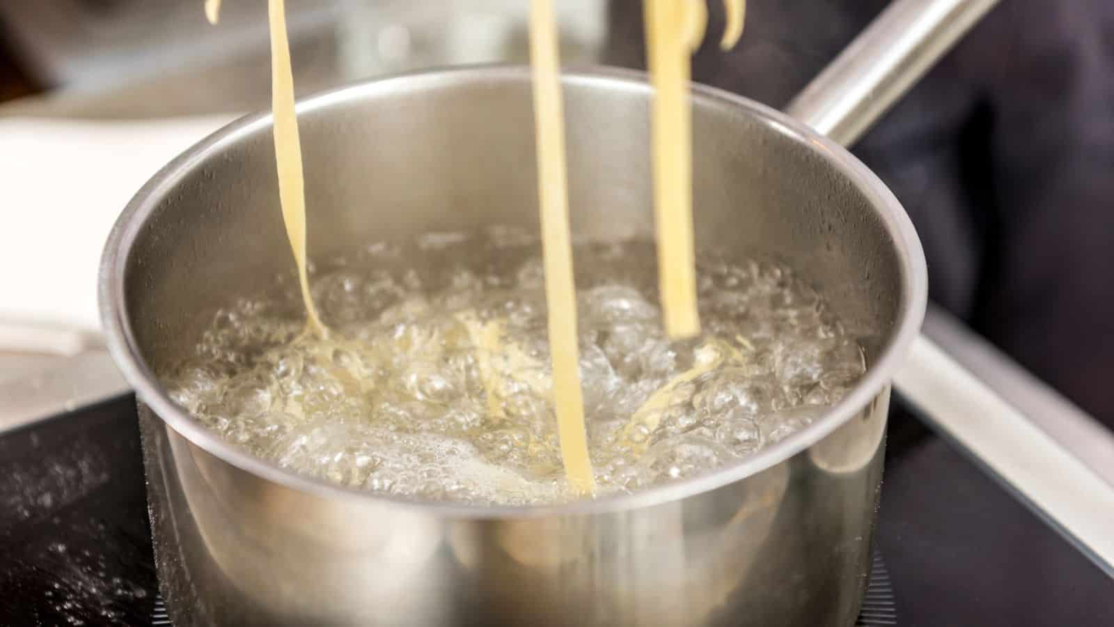 Pieces of pasta being lifted off a saucepan