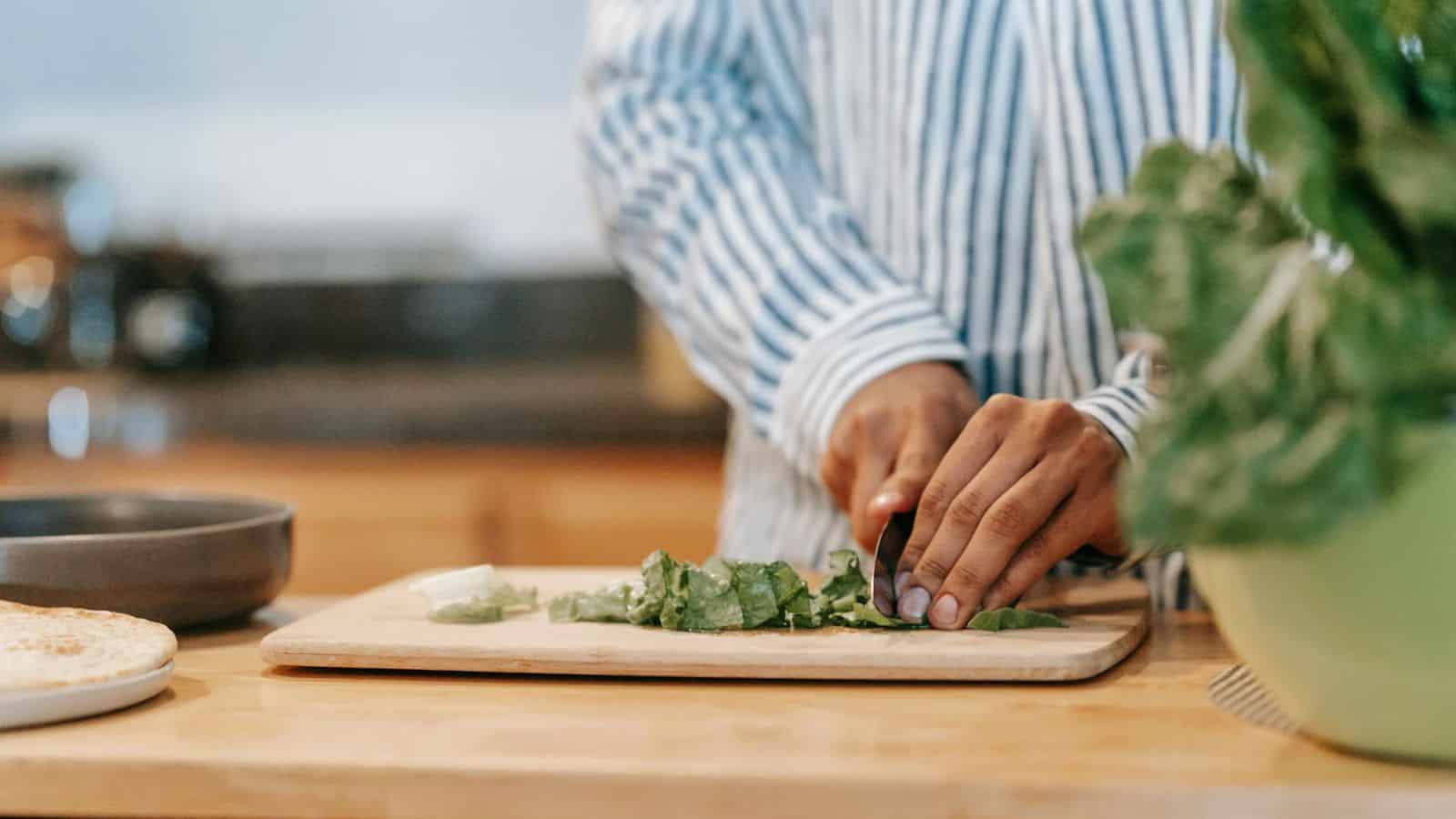 Faceless person cutting spinach leaves