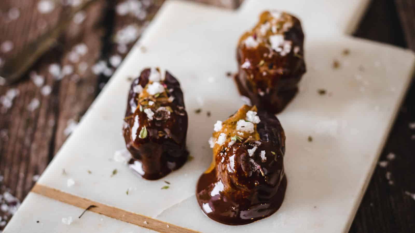 Three stuffed dates on white cutting board.