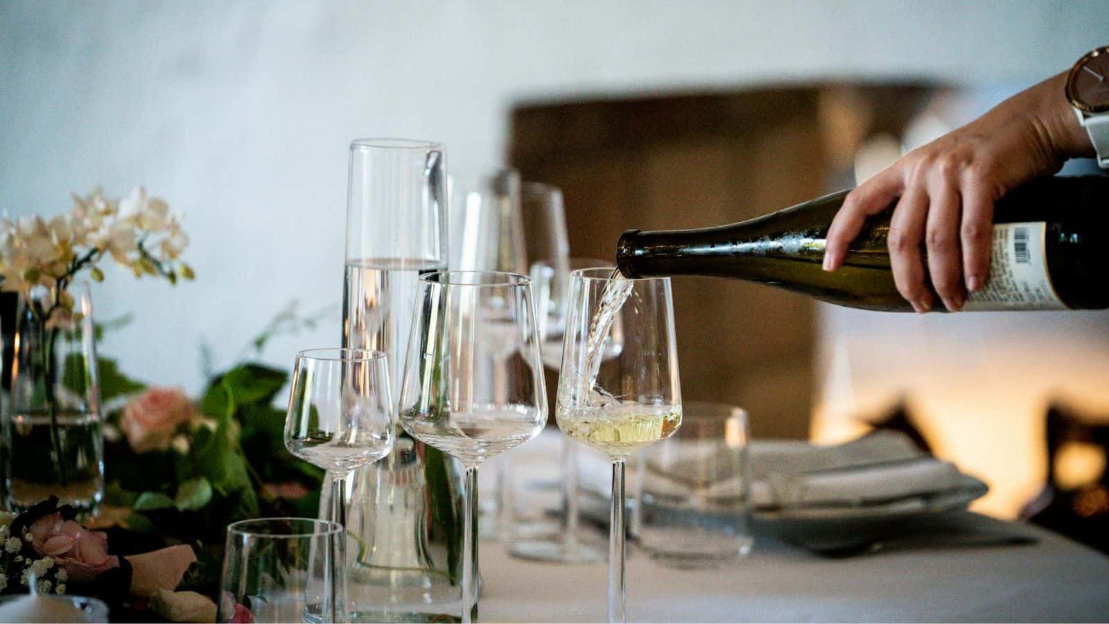 Wine being poured into a glass with other glasses in the background