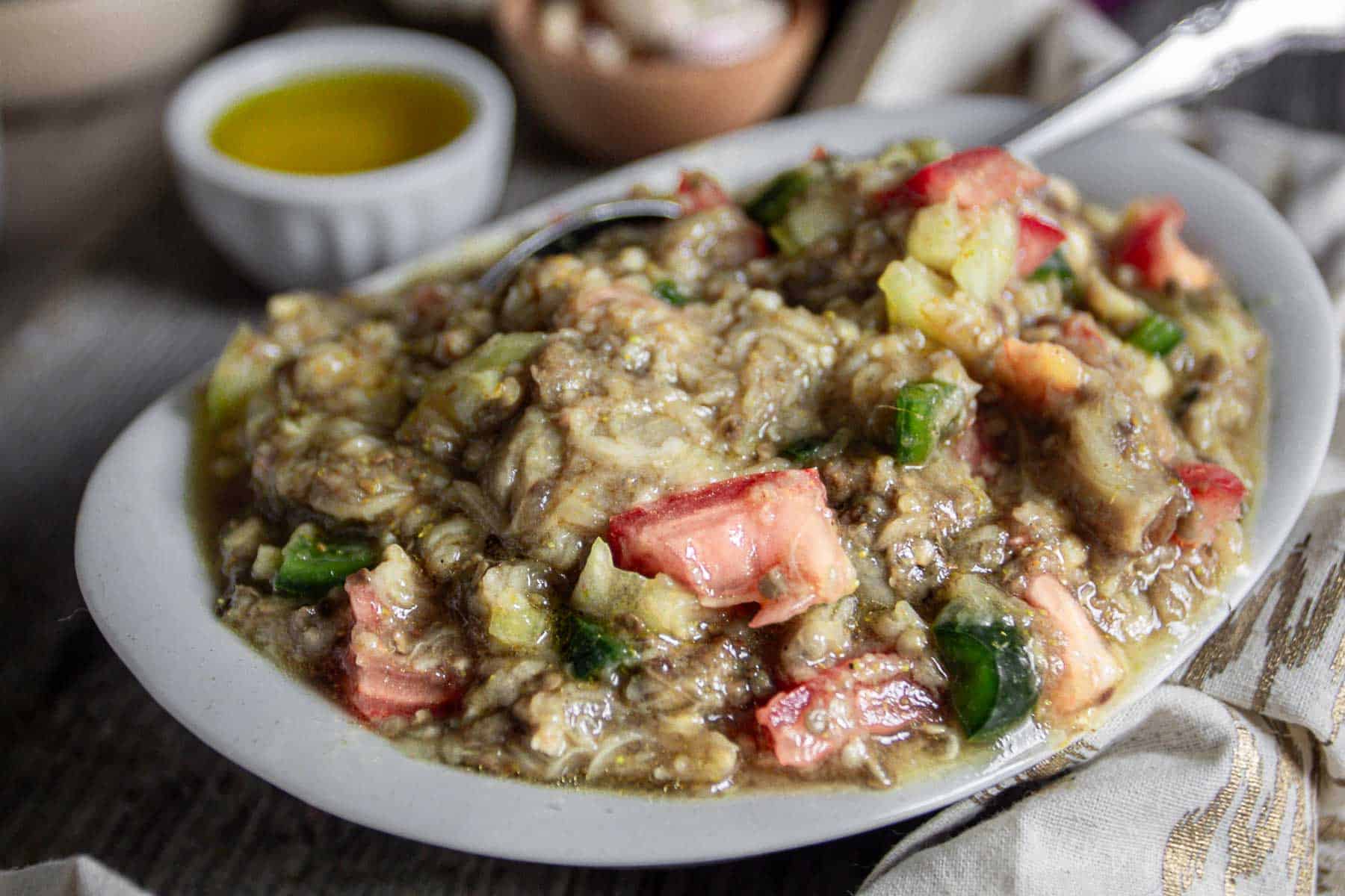 Zaalouk in a white plate with spoon and napkin.