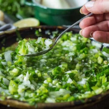 A bowl of aji picante sauce made with chopped green chili peppers, onions, and herbs.