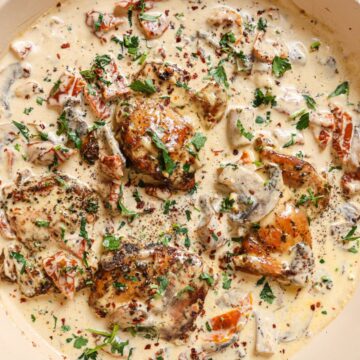 Close up photo of chicken with creamy mushroom sauce in a pan.