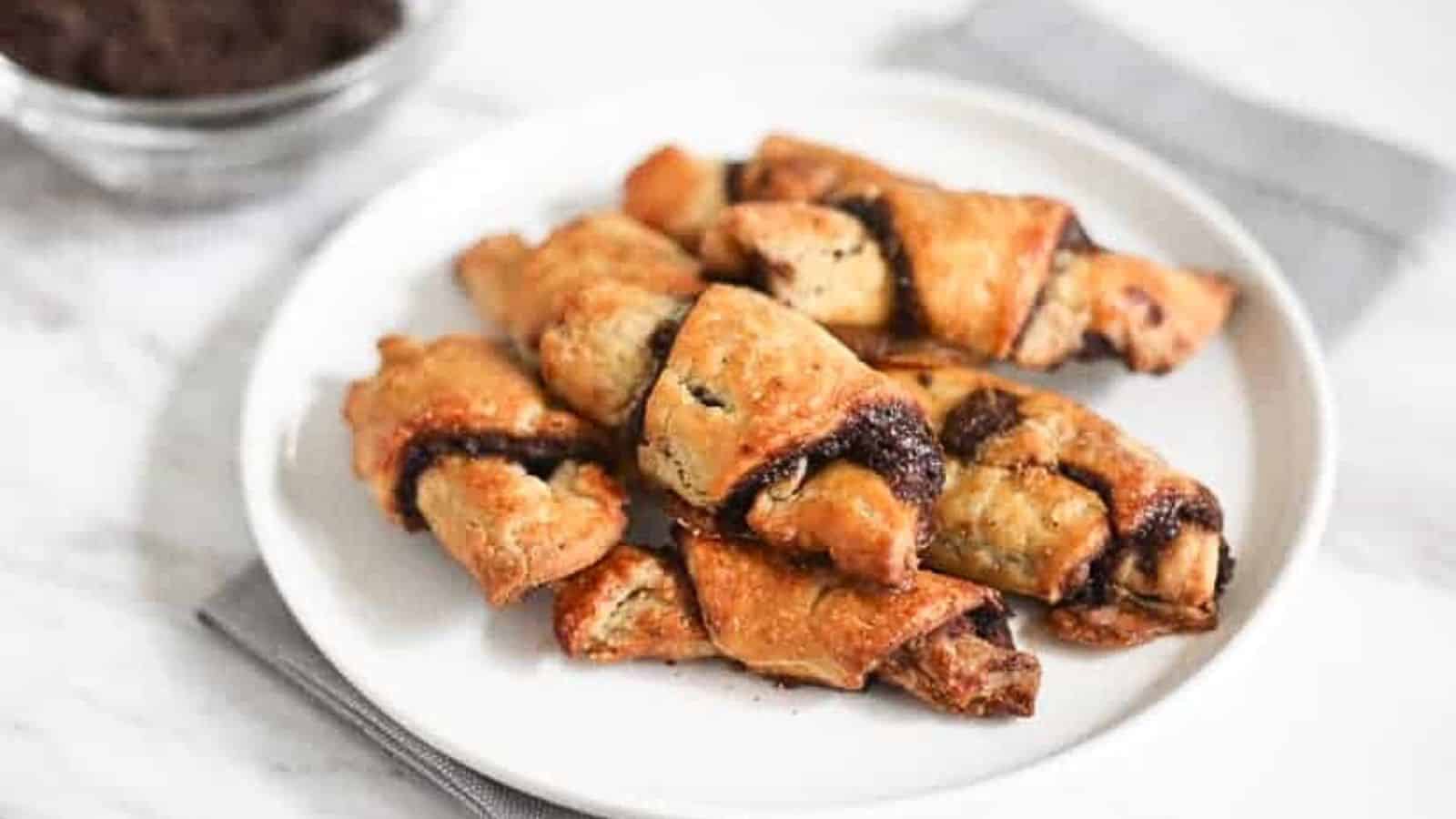 Chocolate croissants on a plate with a cup of coffee.