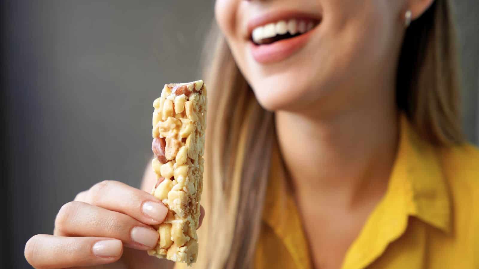 A woman holding an energy bar while laughing