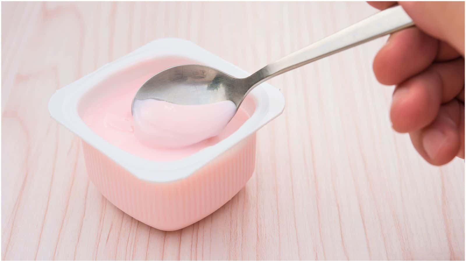 Close-up of a pink-colored yogurt with a spoon dipped in it