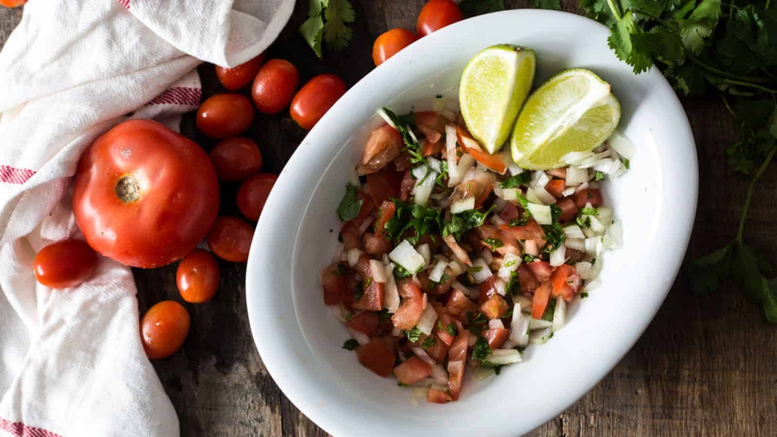 Overhead of pico de gallo in white bowl with veggies around.