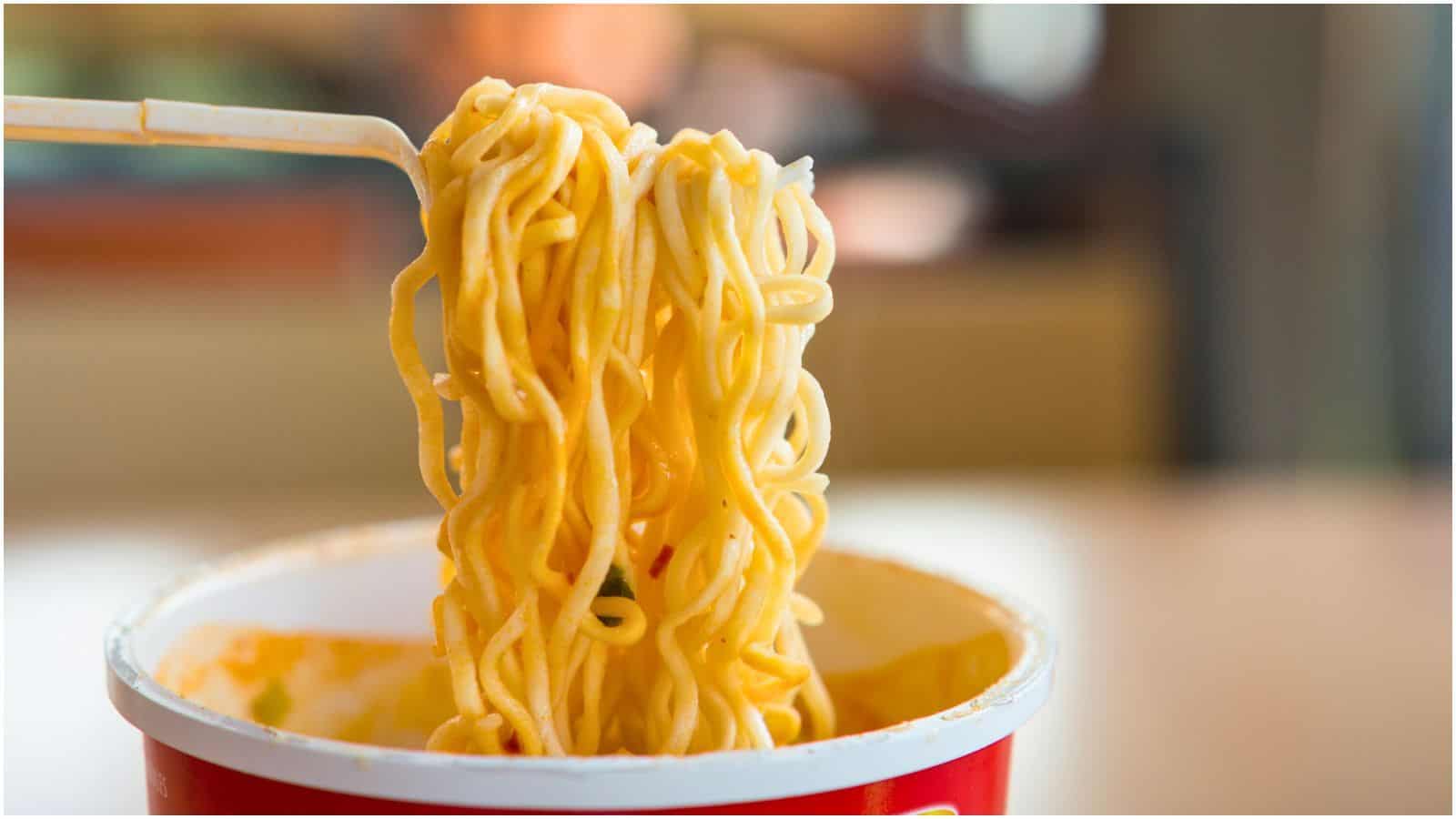 Noodles from a cup of instant noodles being lifted off using a fork