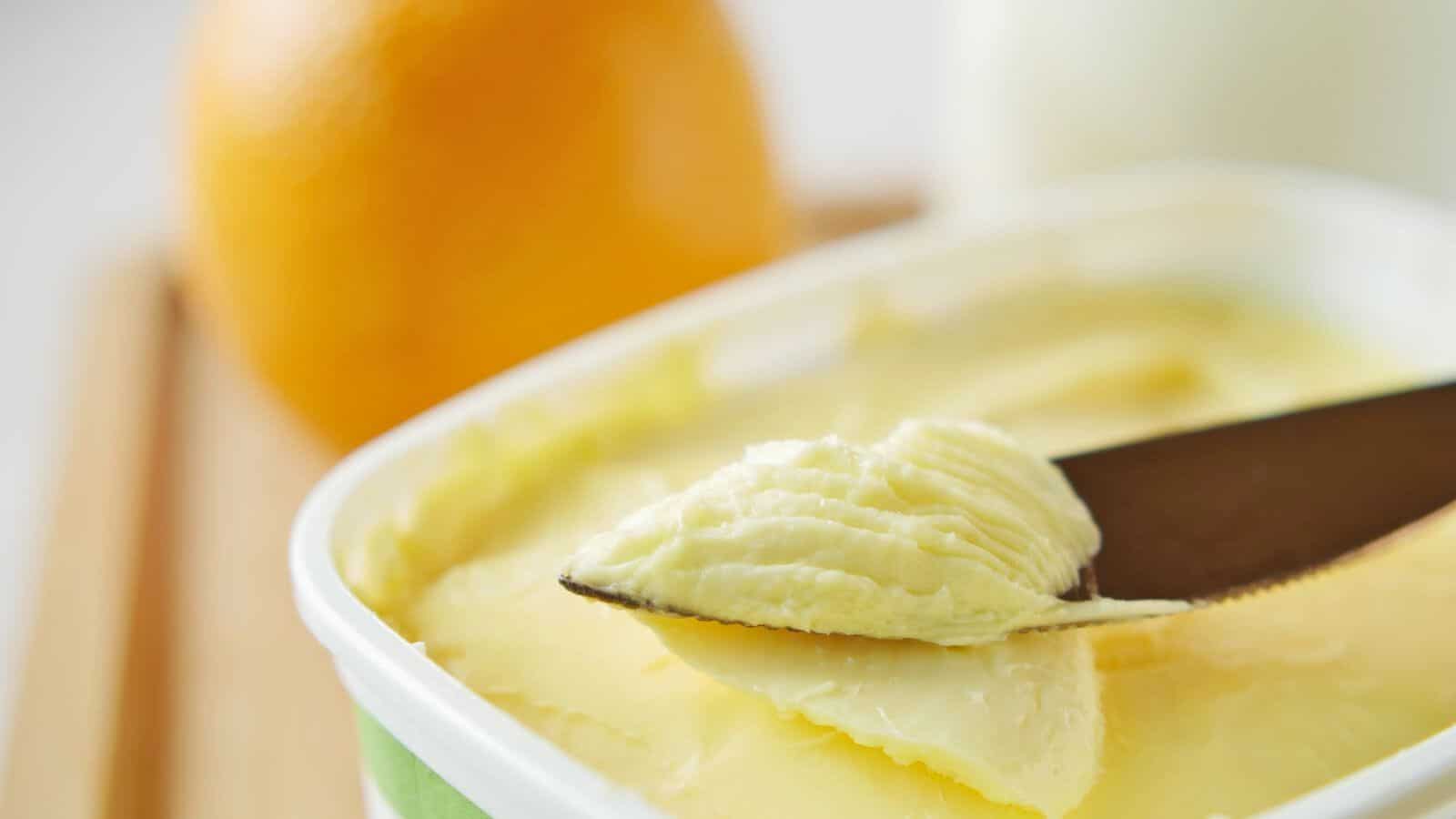 Close-up of a butter knife scooping out some margarine from its container