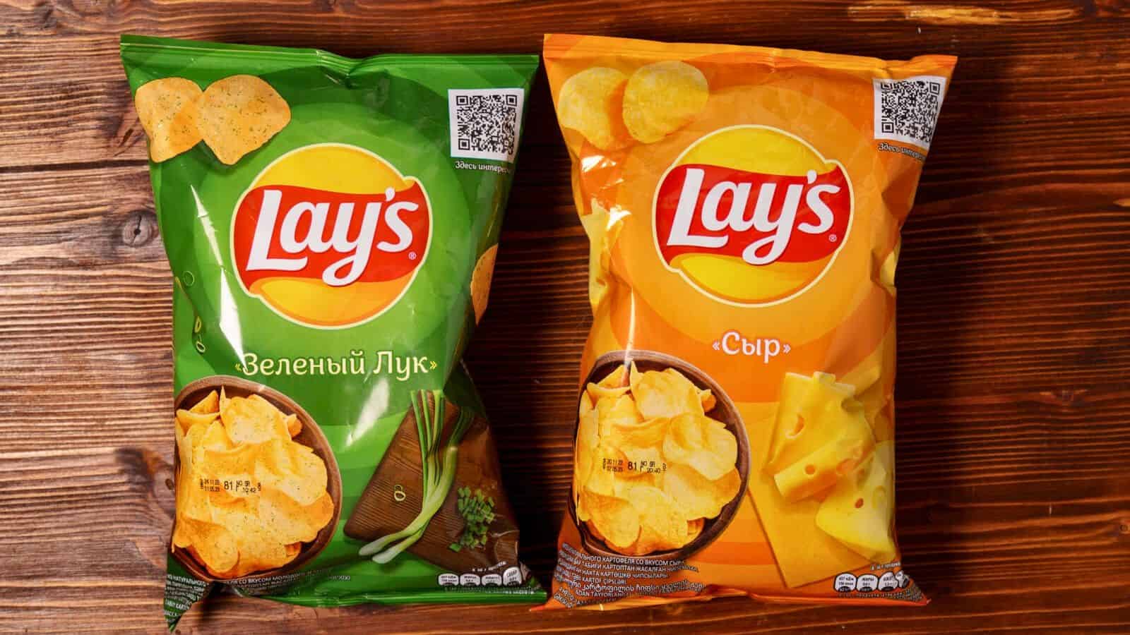 Two bags of Lays chips, one green and one yellow laid side by side