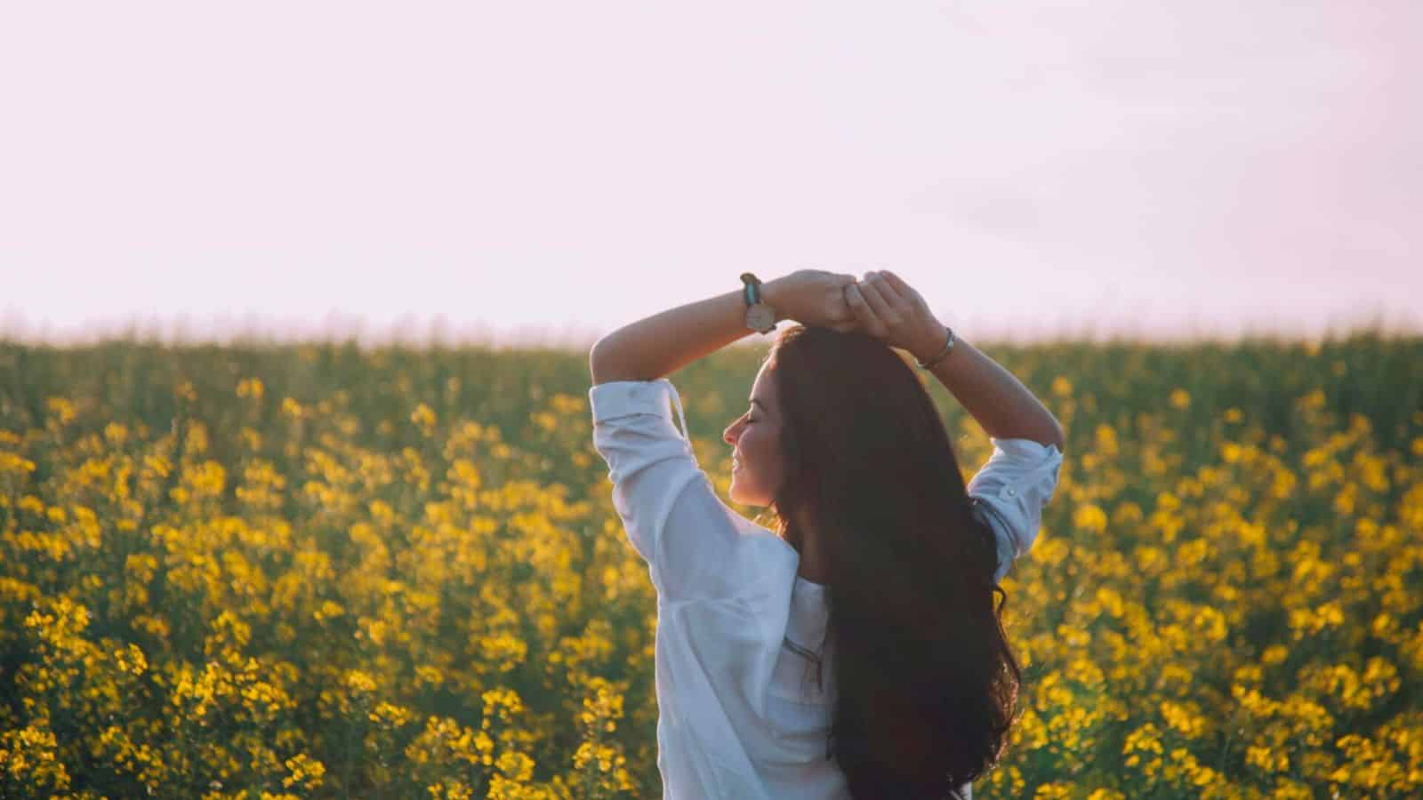 Carefree-looking woman raising her hands in a flower field