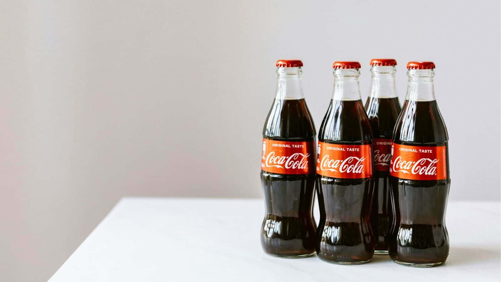 Four bottles of Coca cola on a white table