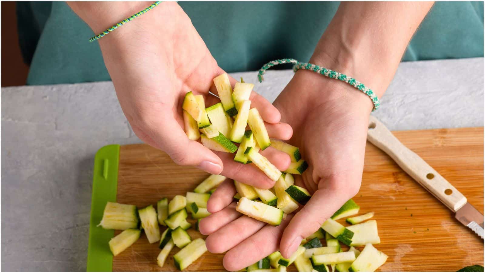 Person holding diced zucchinis on their palms