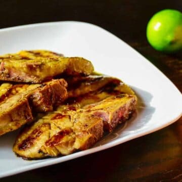 Grilled pork chops on a plate with oranges and limes.