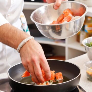 Person cooks salmon on pan