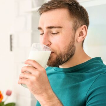 A man drinks milk while closing his eyes