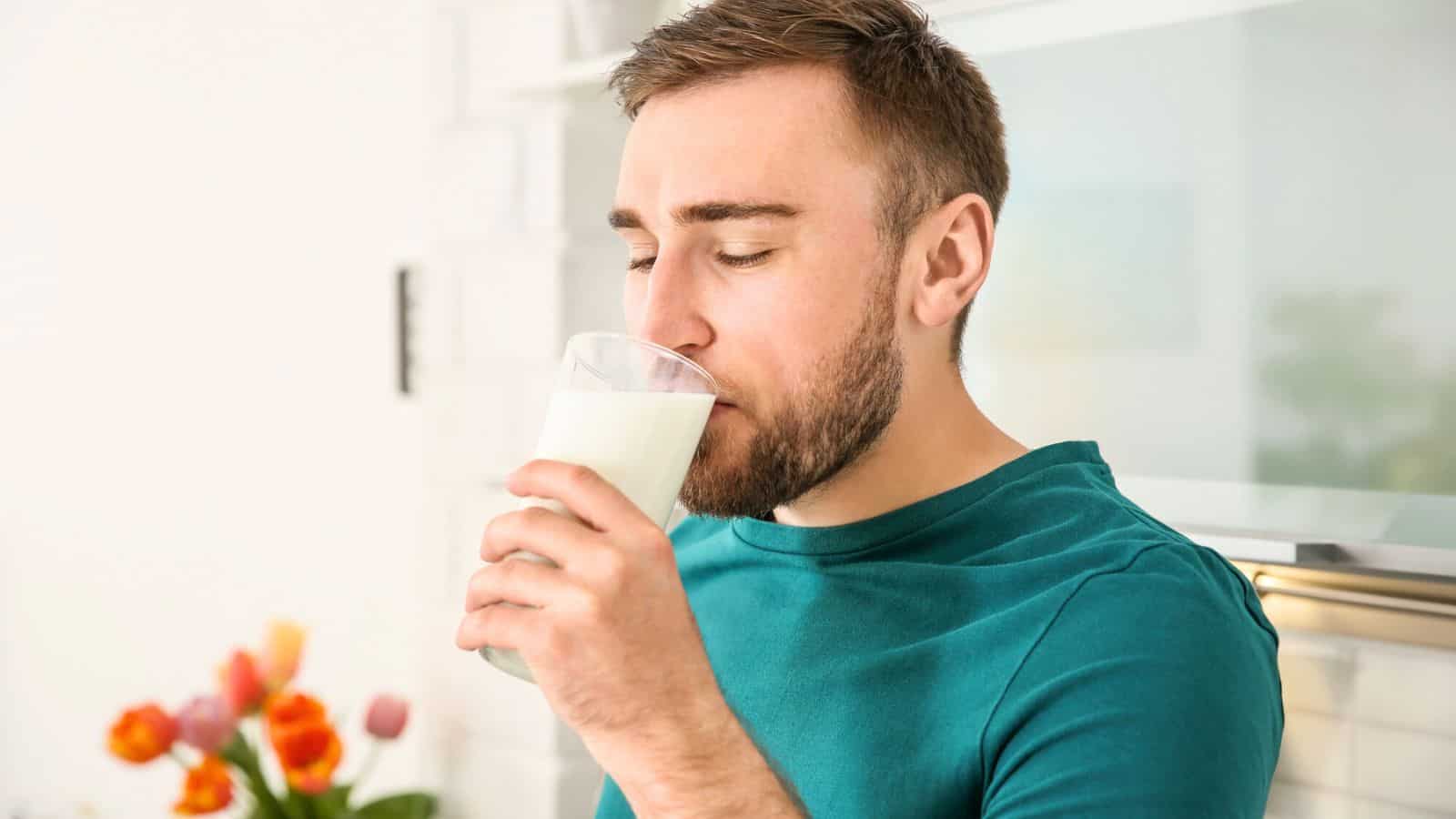 A man drinks milk while closing his eyes