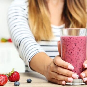 Woman holding a glass of berry smoothie