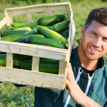 Man holding an entire container of zucchinis