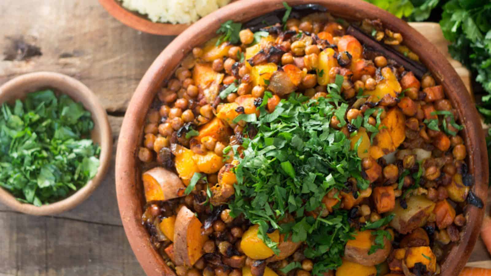 A bowl filled with cooked chickpeas, vegetables, and herbs, garnished with chopped cilantro. The dish appears to be seasoned and colorful. On the side, there is a smaller bowl with more chopped herbs and some greens in the background—an artful auto draft of culinary perfection.