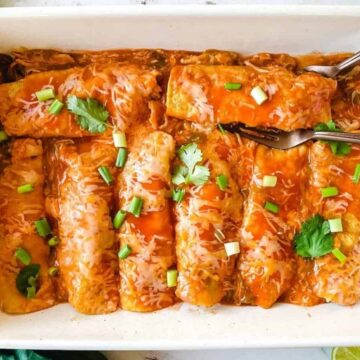 Chicken enchiladas on a white casserole.