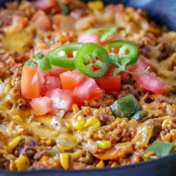 Closeup of a skillet with ground beef, cheese and tomatoes.