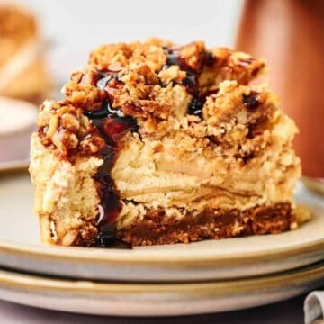 A slice of cheesecake topped with a crumbly streusel and drizzled with dark syrup.