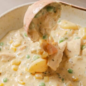 Chicken pot pie soup in a white bowl with a spoon.