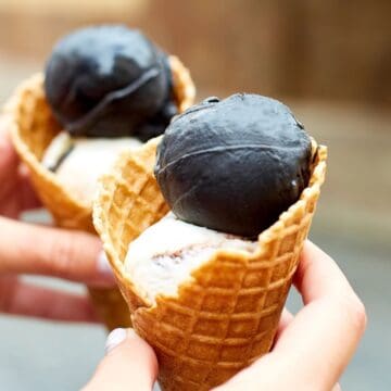 Two hands holding charcoal ice cream cones