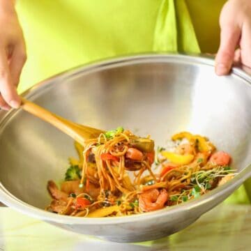 Person stir frying vegetables inside a steel wok