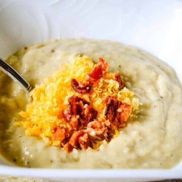 A bowl of loaded parsnip potato soup topped with bacon and cheddar cheese.