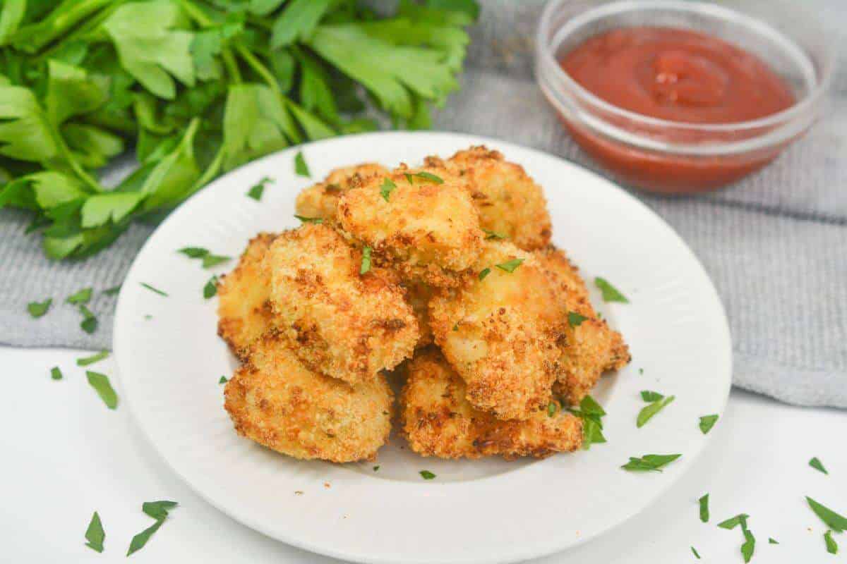 Air fryer chicken nuggets on plate with ketchup.