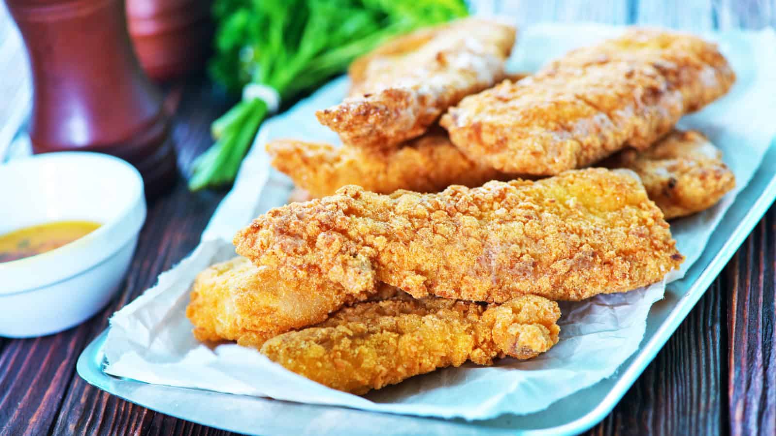 An image of fried catfish on a white rectangular ceramic plate.