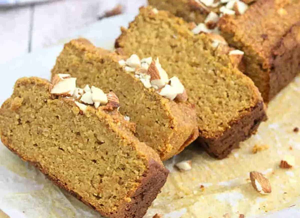 Healthy pumpkin bread in slices on a cutting board and around it with peanut butter on the side.