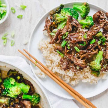 Beef and broccoli stir fry served with white rice on a white plate.