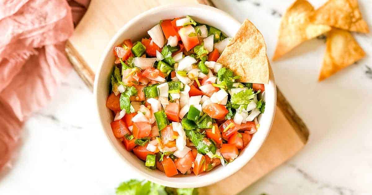 A closeup side shot of garden fresh salsa in a white bowl.