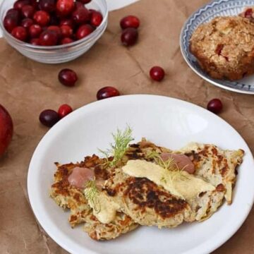 Apple potato latkes with curried yogurt sauce and applesauce on a white plate.