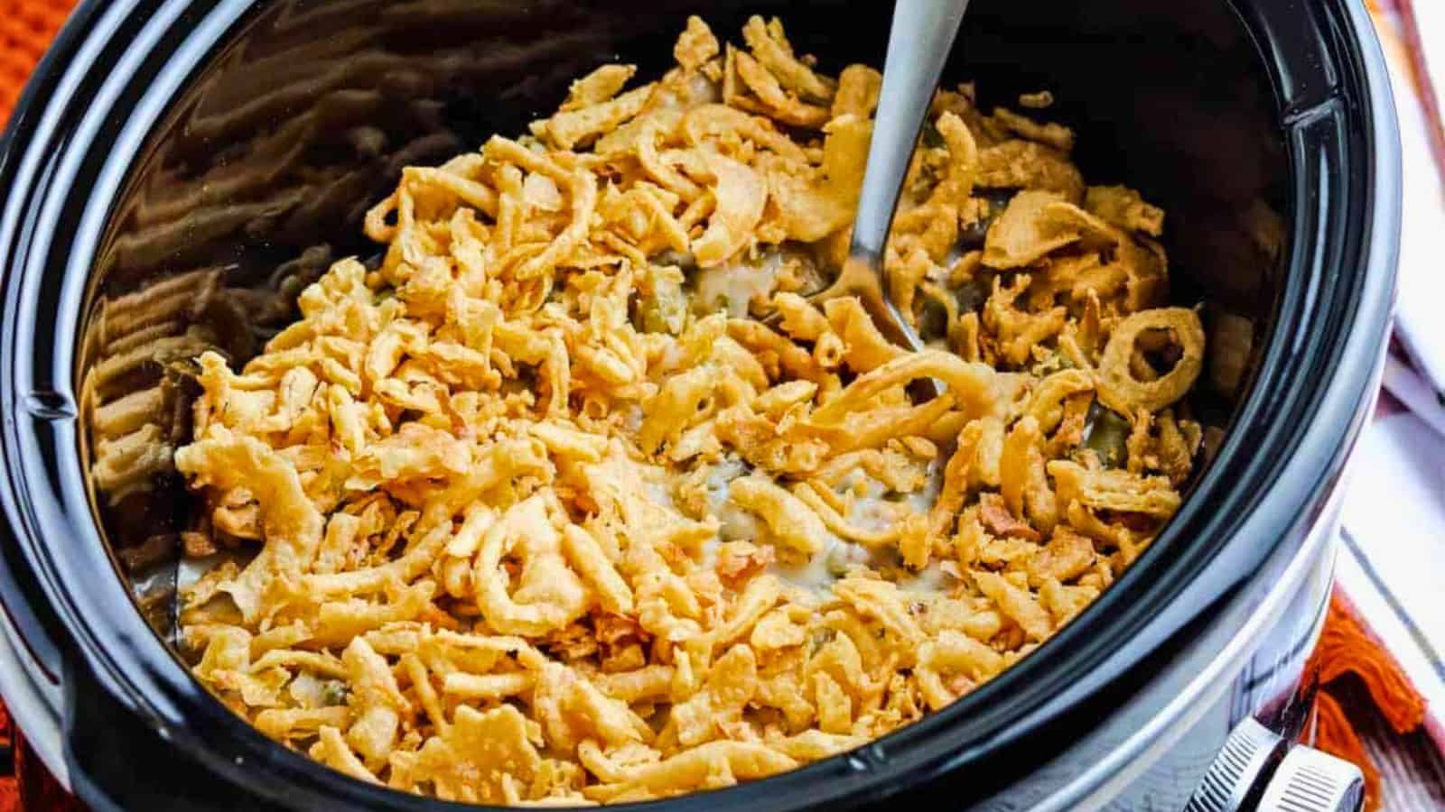 Slow cooker with green bean casserole topped with fried onions.