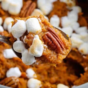 Crock pot with sweet potato casserole with pecans and marshmallows.