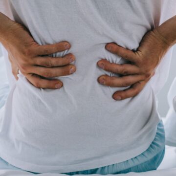 A person with their two hands at their lower back while sitting down.
