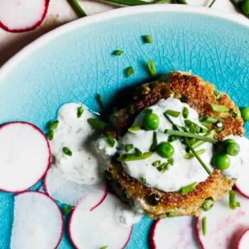 A veggie patty topped with creamy sauce, green peas, and chives, served with sliced radishes on a blue plate—one of our favorite simple dinner recipes.