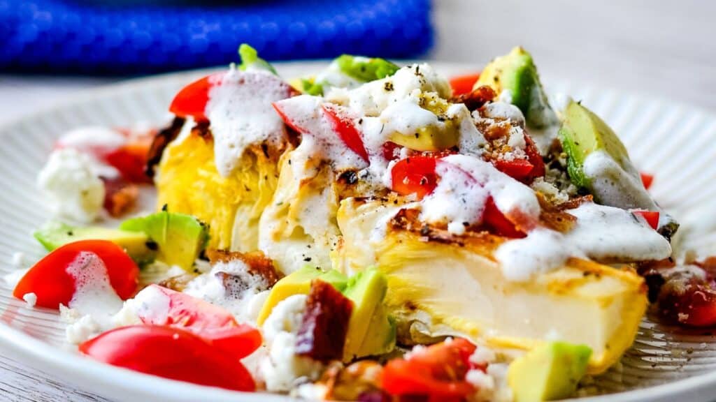 Roasted cabbage steak topped with tomatoes, bacon, goat cheese, and more.