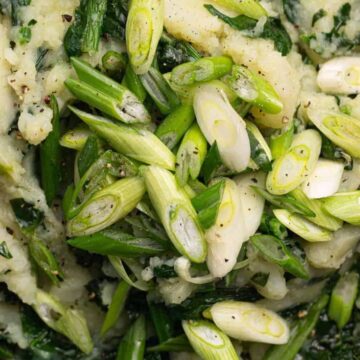 A bowl of colcannon, a traditional Irish dish and a good choice for sides, features mashed potatoes mixed with green leafy vegetables and topped with chopped scallions. Perfect to share at any gathering.