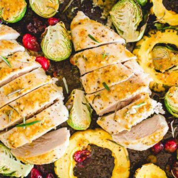 Roasted chicken with cranberries and brussels sprouts on a baking sheet.
