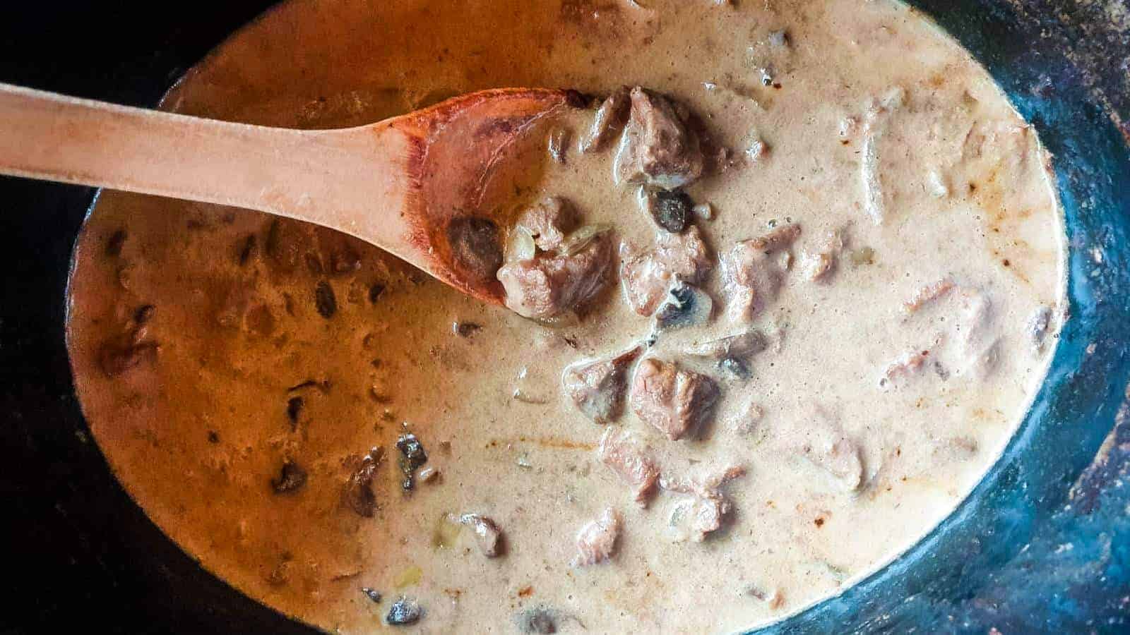 Crockpot beef stroganoff with wooden spoon.