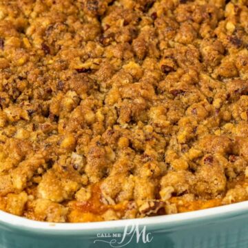 A close-up of a baked dish featuring a sweet potato casserole with a crumbly pecan topping in a rectangular teal baking dish. This easy side will steal the spotlight, perfectly resting on a light-colored surface.