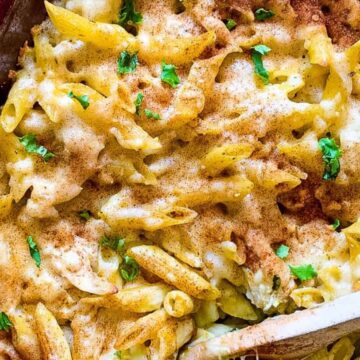 Penne and chicken in a casserole dish with pesto and cheese.