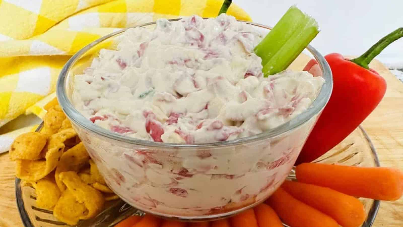 A bowl of dip with carrots and celery.